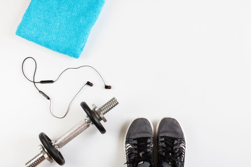 A pair of dumbbells, a skipping rope and trainers on a white floor